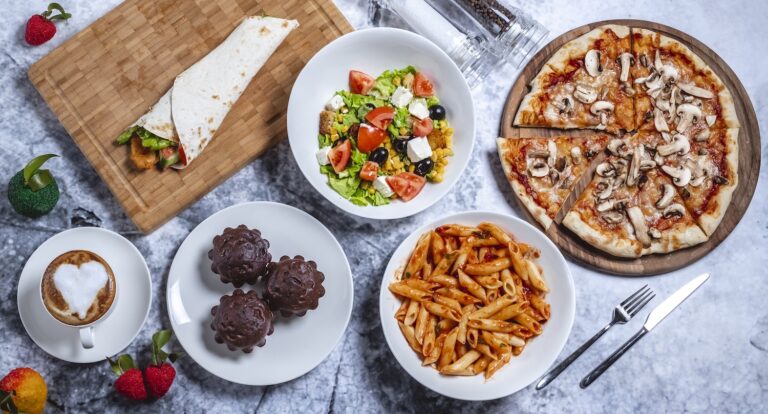 An appetizing spread of food including pizza, salad, pasta, coffee, and desserts.